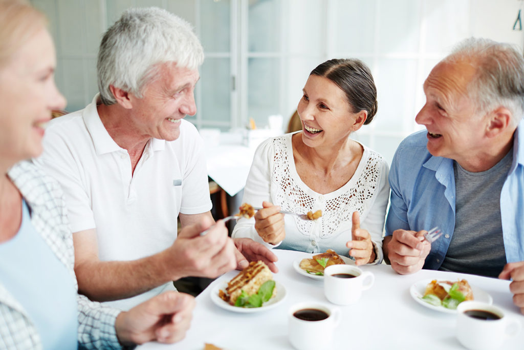 Group of Elderly people smiling and laughing at a table