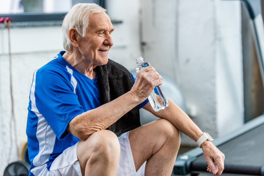Elderly athletic man, drinking a bottle of water sitting down