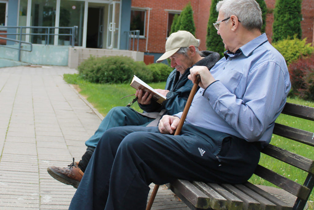 Two elderly men sitting together and talking on a bench