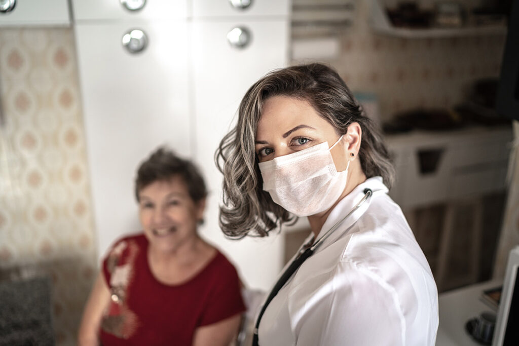Assisted living nurse wears a mask and tends to a patient