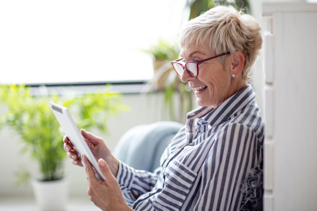 Good looking senior woman smiling and using tablet