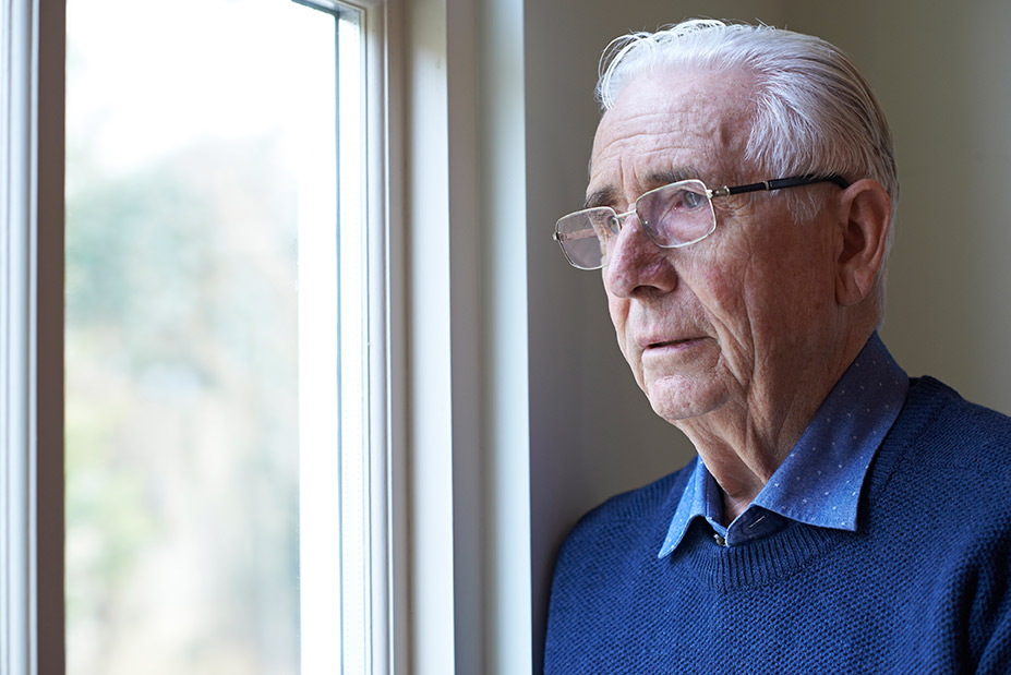 Depressed elderly man looking out the window